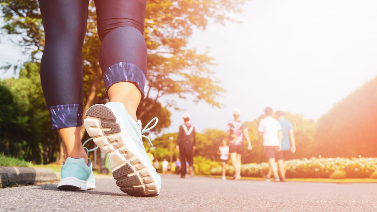 Young fitness woman legs walking with group of people exercise walking in the morning